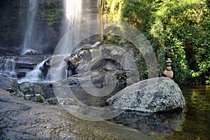 Tropical waterfall with a totem and sunray