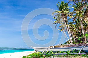 Tropical white beach view and lonely sailboat near palm trees