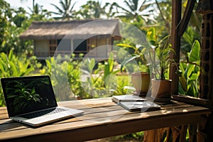 Tropical workplace. Work on vacatoin. Online working, laptop on wooden table outside a thatched hut