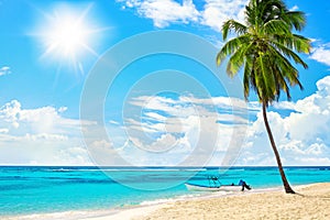 Tropical yellow sand beach landscape, turquoise sea water, blue sky,  bright sun, white clouds, palm tree, boat, summer holidays