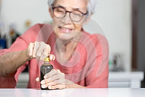 Trouble opening the lid of the bottle in the elderly aged,fingers without strength and weak,senior woman trying hard to open the