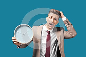 Troubled businessman with clock on color background. Time management concept
