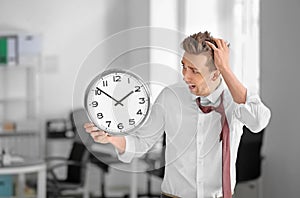 Troubled businessman with clock in office. Time management concept