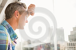 Troubled casual businessman leaning against window