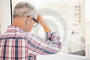 Troubled casual businessman leaning against window