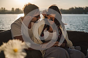 Troubled couple holding hands while sitting by the river