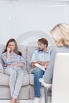 Troubled couple sit with arms folded