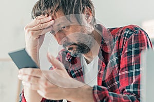 Troubled disappointed freelancer using smartphone for communication