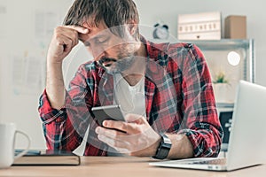Troubled disappointed freelancer using smartphone for communication