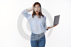 Troubled insecure female office newbie hold laptop, look concerned puzzled, panicking, open mouth gasping nervous grab