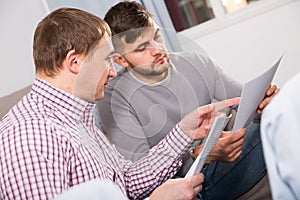 Troubled man discussing documents with partner on couch