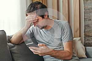 Troubled man receiving bed news in text message on mobile phone