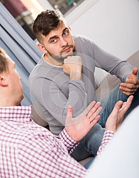 Troubled man talking with friend on sofa