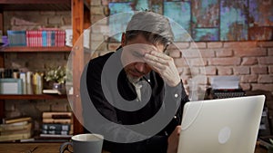 Troubled mature man working at home office with laptop