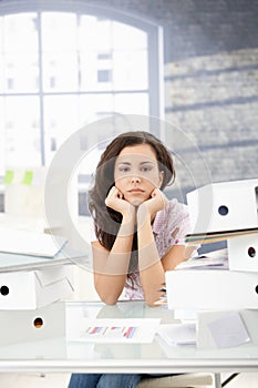 Troubled secretary sitting among folders