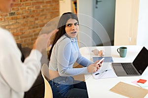 Troubled teen girl using cellphone while her mom arguing and forbidding something, having quarrel with parent