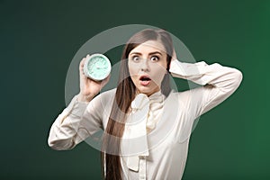 Troubled woman with alarm clock on color background. Time management concept