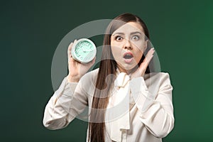 Troubled woman with alarm clock on color background. Time management concept