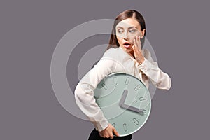 Troubled woman with clock on grey background. Time management concept