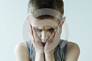 Troubled Young Boy Holding Face in Hands