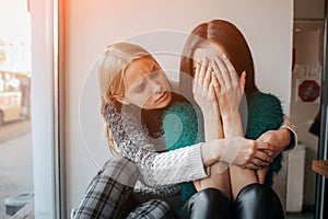 Troubled young girl comforted by her friend. Woman supporting the girl