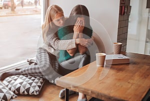 Troubled young girl comforted by her friend. Woman supporting the girl