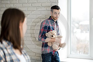 Troubled young handsome man, woman at the background. Family relationship problems concept.