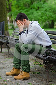 Troubled young man sitting in the park photo
