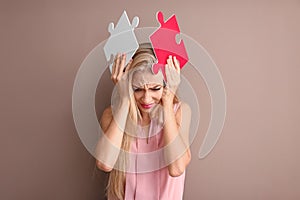 Troubled young woman with pieces of puzzle on color background