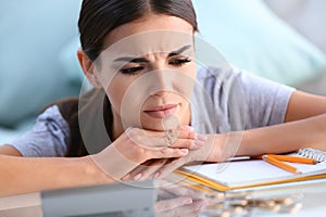 Troubled young woman thinking about bills while sitting at table