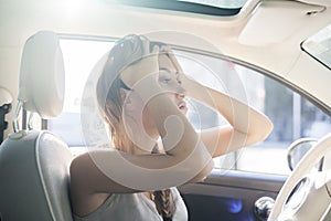 Troubles on the road, tired woman touches her forehead by hands while in a car