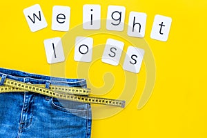 Trousers with measuring tape and weight loss concept for sport concept on yellow background top view