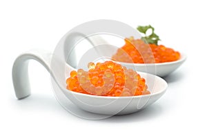 trout eggs in a white ceramic spoon on white background