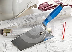 Trowel with folding rule, hard hat, working gloves and pencil on