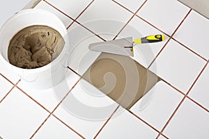 Trowel and old white tiles with tile adhesive