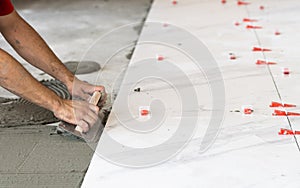 Troweling mortar onto a concrete floor in preparation for laying white floor tile