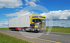 Truck with blue-yellow cabin moving on highway.