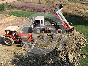 Truck and bulldozer dirt leveling on plot of land
