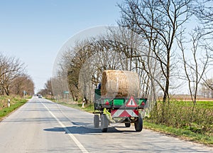 Truck carries one hay roll along asphalt road