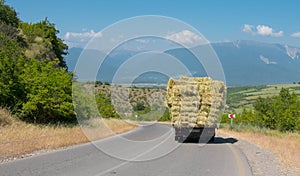 The truck carries rolls of hay. Ivanovka mounatain village of Ismailli region of Azerbaijan. Village life.