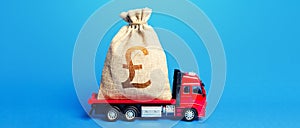 Truck is carrying a huge british pound sterling money bag. Great investment. Anti-crisis measures of government. Attracting large