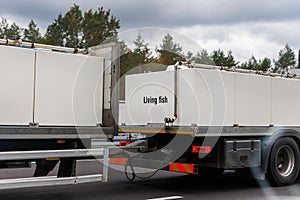 Truck carrying live fish big white tanks highway with forest background. Semi trailer cargo vehicle motorway photo