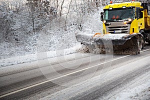 Truck cleaning on winter road covered with snow