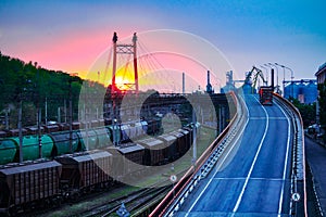 Truck with container rides on the road, railroad transportation, freight cars in industrial seaport at sunset