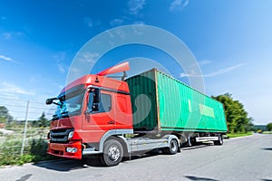 Truck with container on the trailer is driving on the road