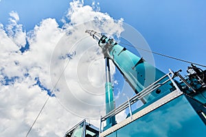 Truck crane with outstretched boom on blue sky background