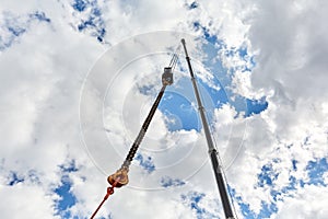 Truck crane with outstretched boom on blue sky background