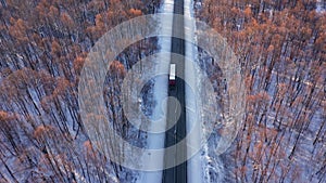 The truck crosses a large snow-covered forest. Drive on the highway at low speed. Compliance with safety measures on the