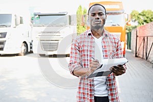 Truck driver checking shipment list while standing on parking lot of distribution warehouse