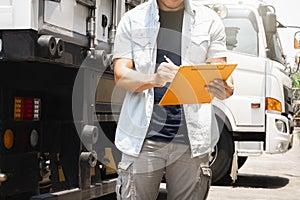 A truck driver holding clipboard checking checklist safety a truck trailer.